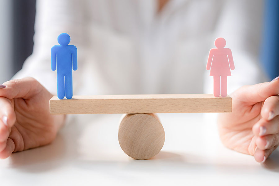 Figure maschile e femminile in equilibrio su una bilancia di legno