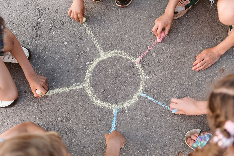 Bambini che disegnano insieme un sole con i gessetti colorati